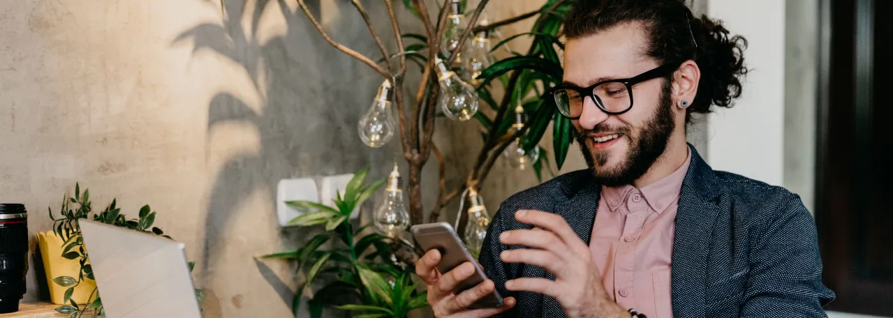 Pessoa sorrindo ao celular enquanto envia uma mensagem pelo WhatsApp