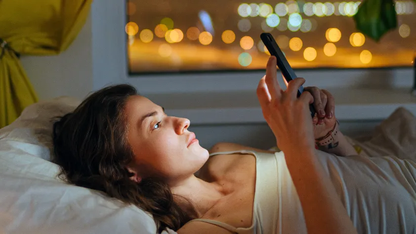 Pessoa deitada na cama lendo uma mensagem do WhatsApp após clicar em um anúncio