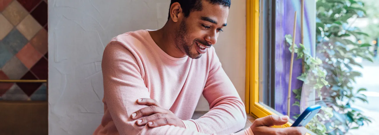 Pessoa sentada em uma cafeteria enviando mensagens pelo WhatsApp