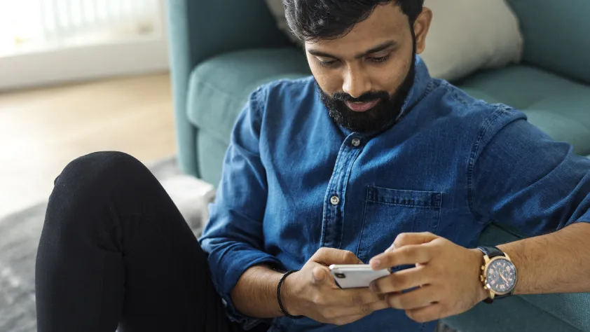 Pessoa sentada no chão contra um sofá enquanto lê uma mensagem personalizada no WhatsApp