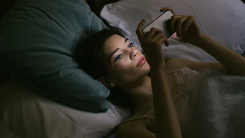 Persona acostada en la cama interactuando en una conversación de WhatsApp Business para realizar una compra