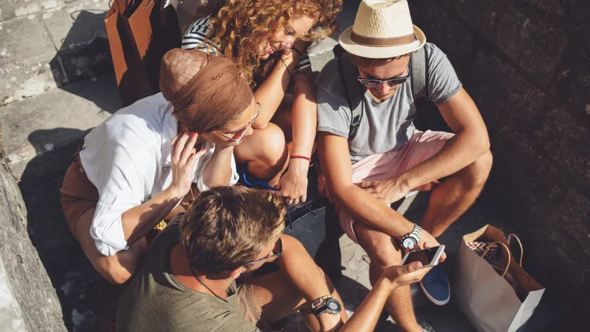 Group of four people sitting on steps looking at a product catalog sent through WhatsApp