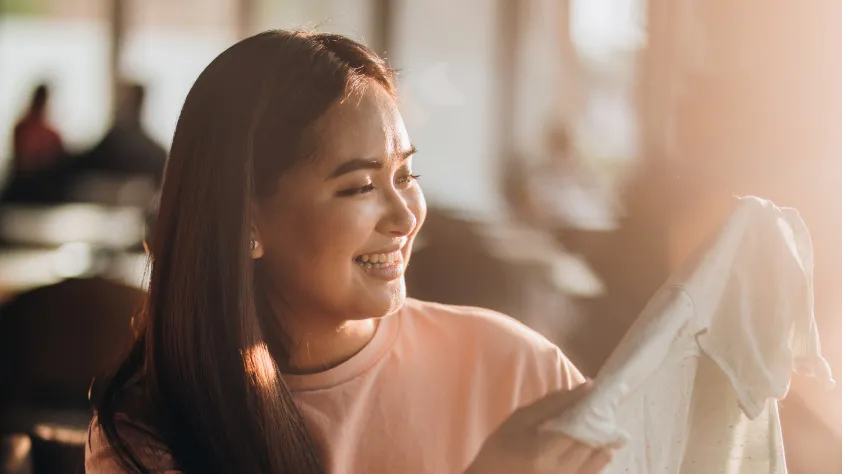 Persona sonriendo mientras sostiene una prenda