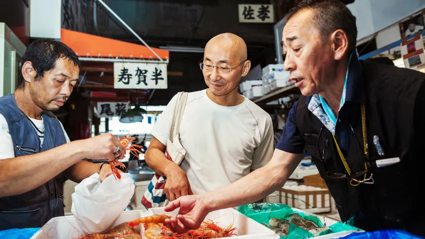 Three people purchasing shrimp from fish market