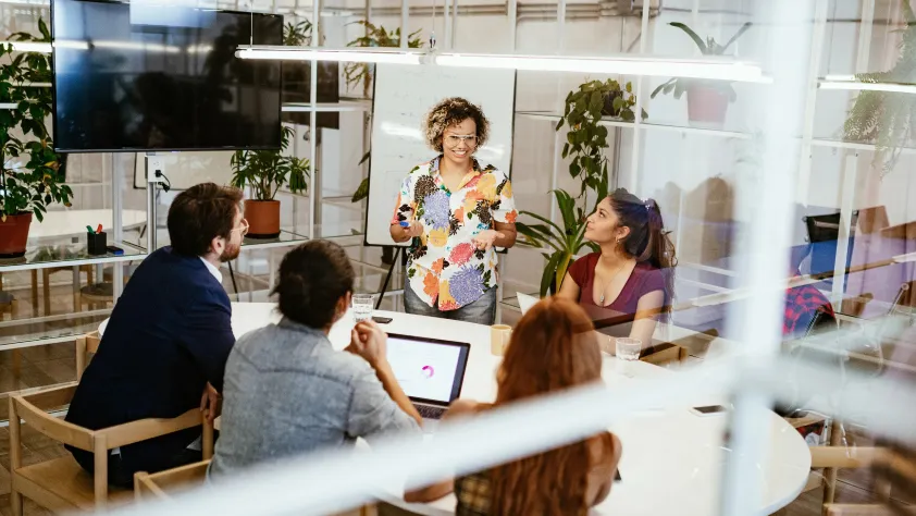 Person leading a group meeting of six people in a conference room