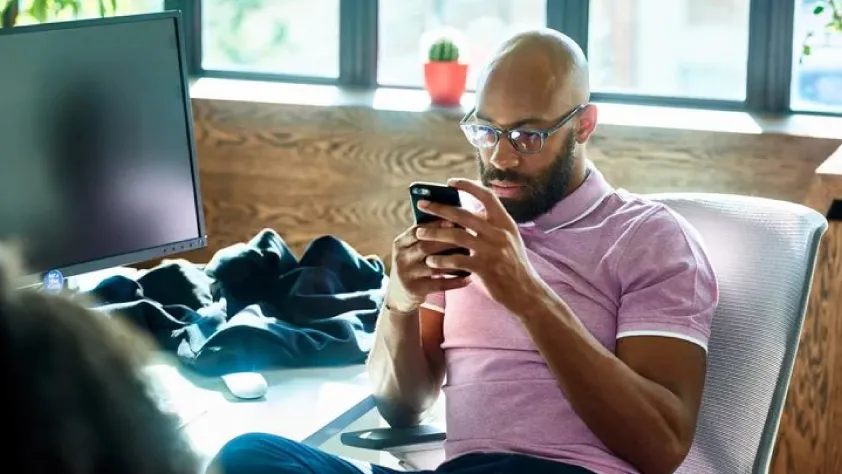Person sitting at desk scrolling through phone