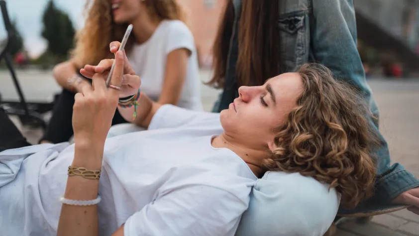 Person lying in someone's lap while checking phone