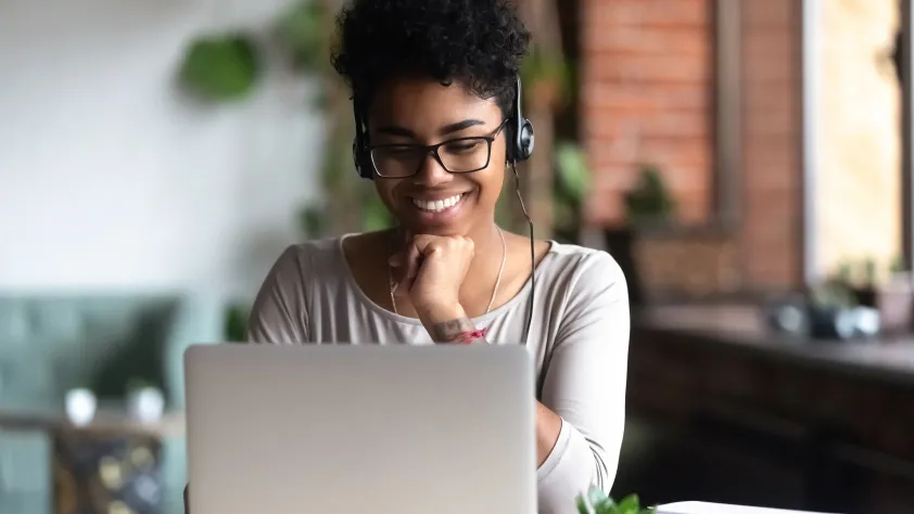 Person wearing headphones smiling at laptop