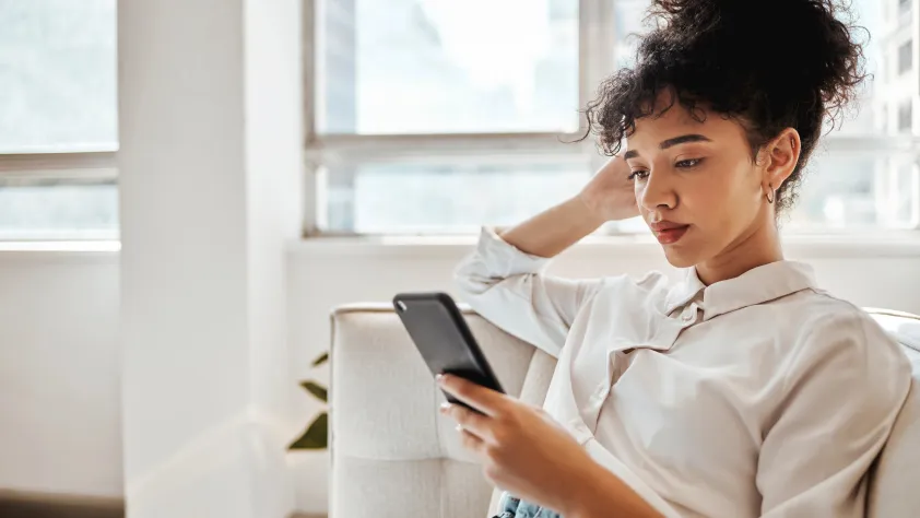 Person sitting on couch while reading a message via WhatsApp
