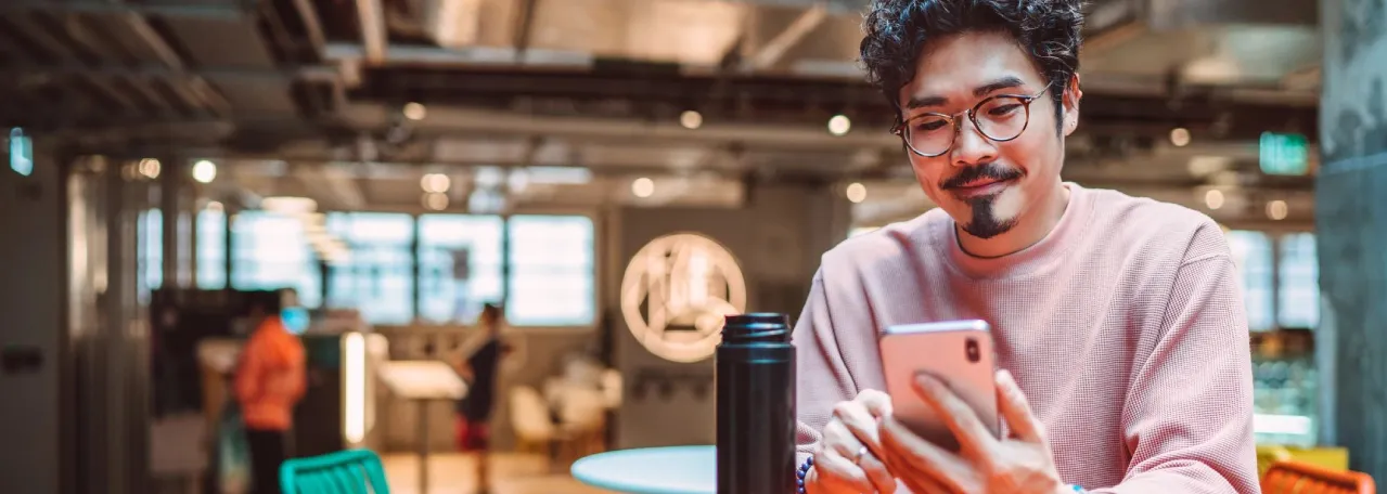 Person with glasses sitting at office scrolling on phone