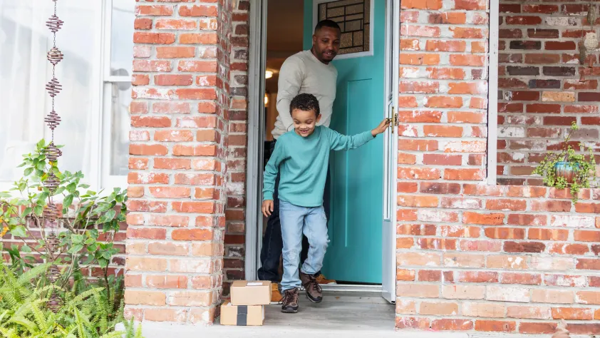 Parent and child walking out of house door to pick up packages