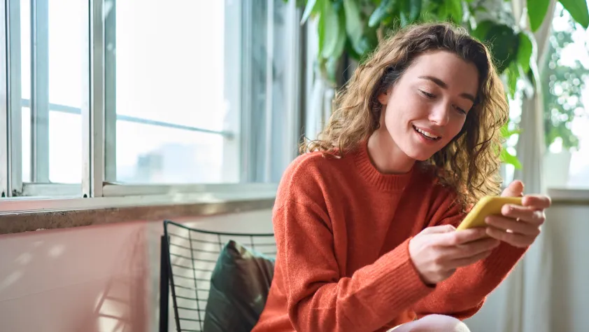 Person sitting on chair reading a message on WhatsApp