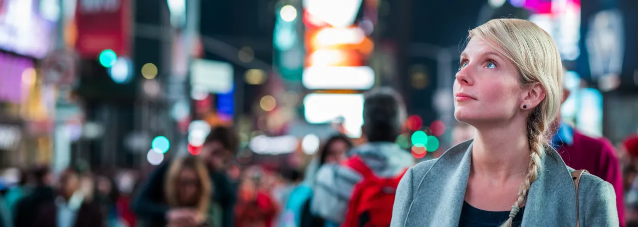 Person in Times Square looking up at an ad amidst crowd