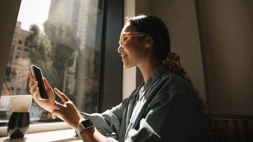Person sitting in front of window while reading a message from Vodafone through WhatsApp