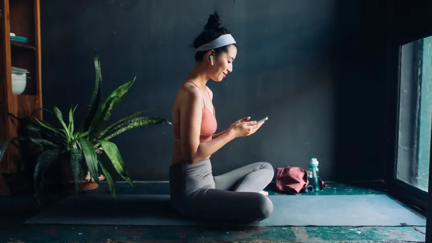 Person sitting on yoga mat after class while checking phone