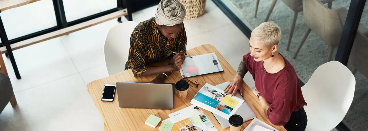 Aerial view of two people working around a table and sharing ideas through presentations