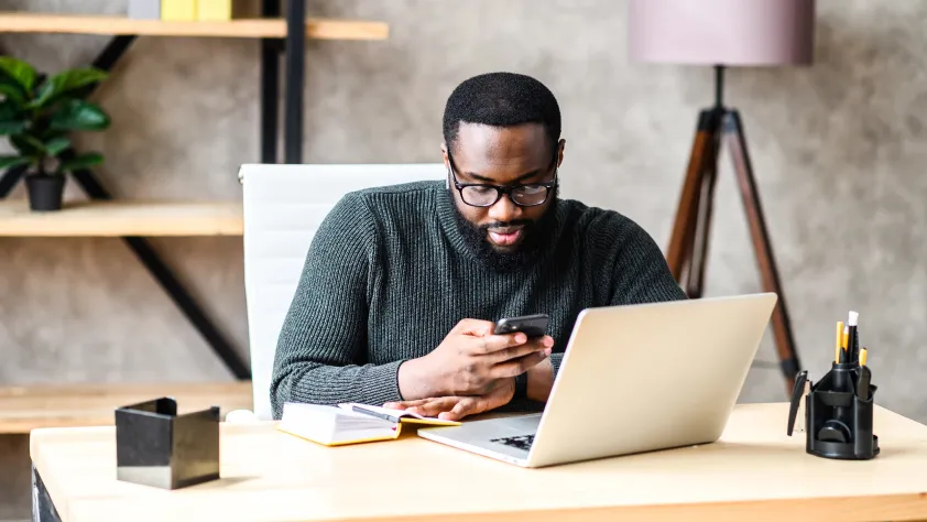 Person sitting at desk in home office and while reading a business message on WhatsApp