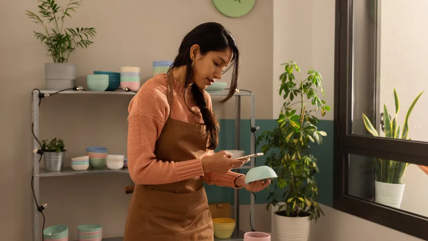 Person in a ceramics studio taking a picture of a bowl to send in a shipping update via WhatsApp