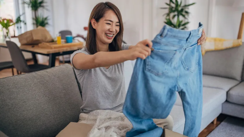 Person sitting on couch opening up package with new jeans