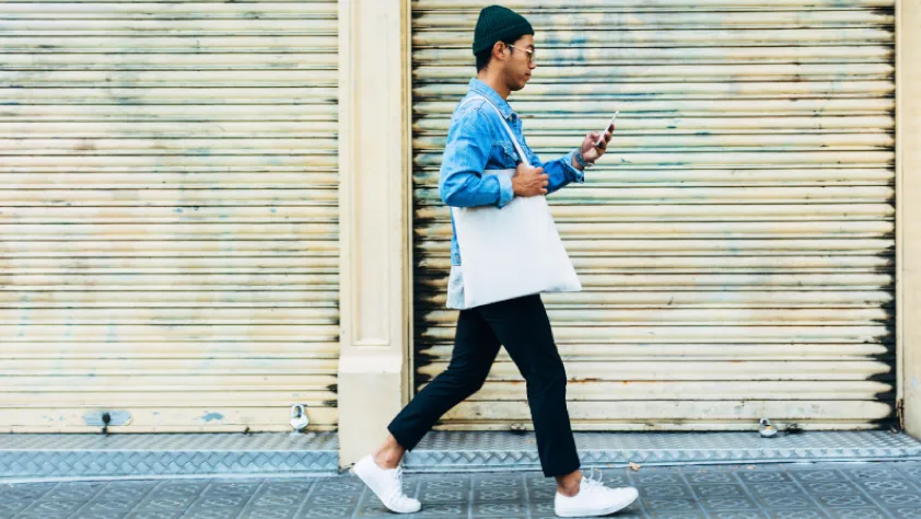 Person walking down the street while sending a WhatsApp message to a business about making a purchase