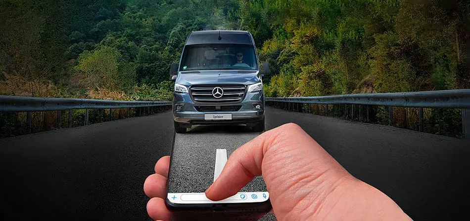 a hand holding a cell phone with a WhatsApp chat and a van and road as background.