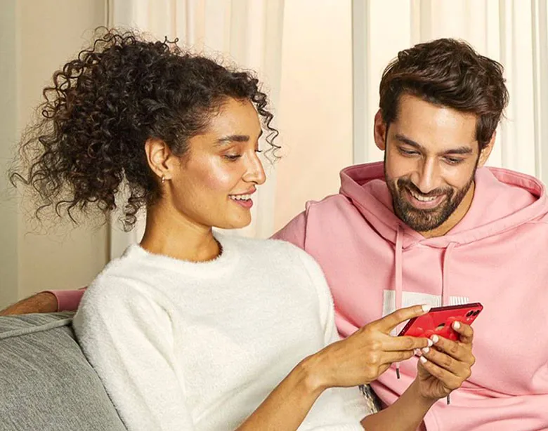 Una pareja sentada en un sofá mira un teléfono