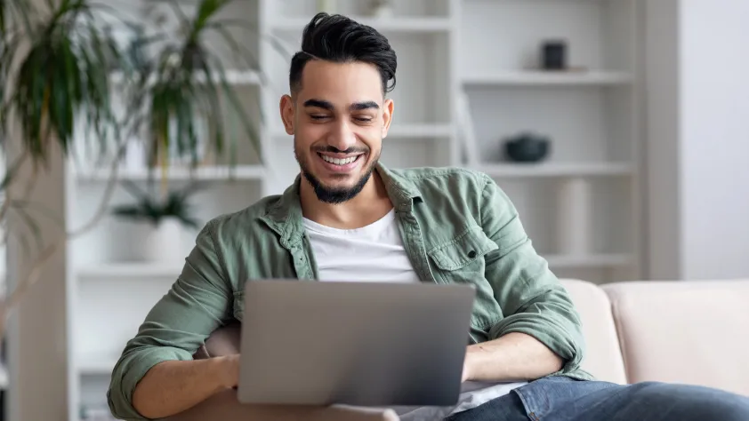 Person sitting on couch in living room viewing a click-to-message ad on laptop