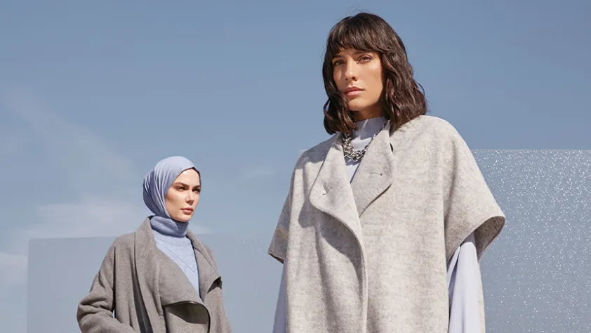 Two people modeling clothes in front of sky blue background