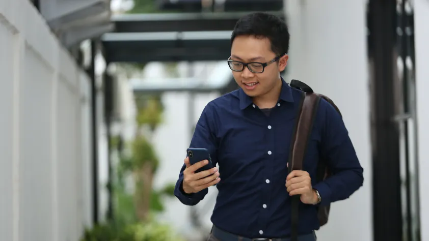 Person walking out of office while reading a business message via WhatsApp