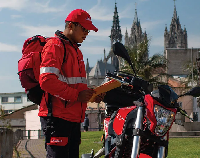 Repartidor de Urbano Envíos parado junto a una motocicleta