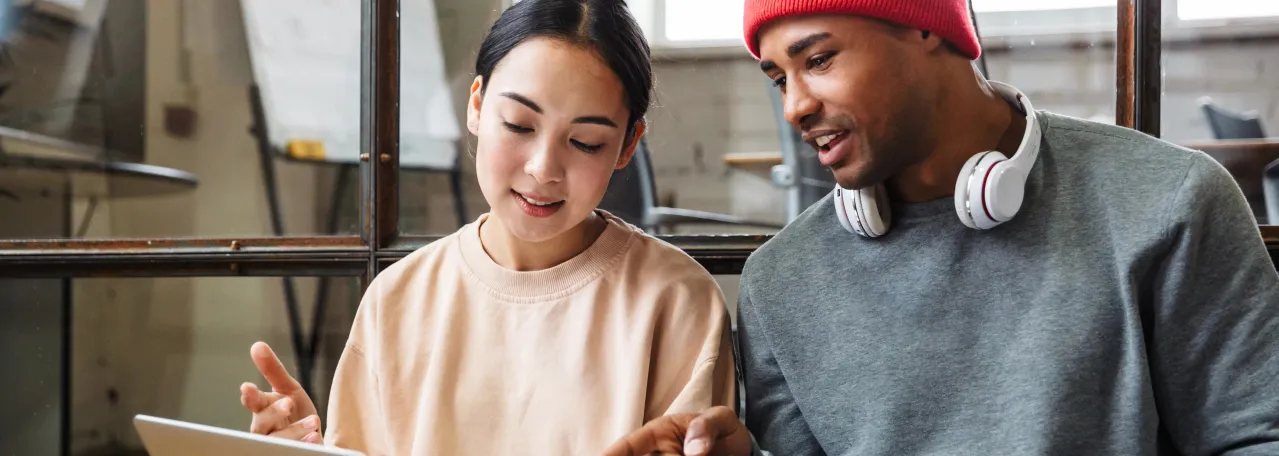 Two people in an art studio working on a design on their laptop