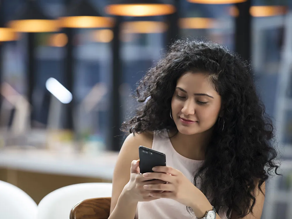 A smiling, young woman looking at a phone