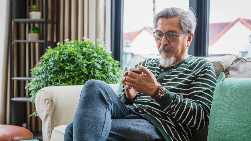 Person sitting on couch in cafe while reading a business message via WhatsApp