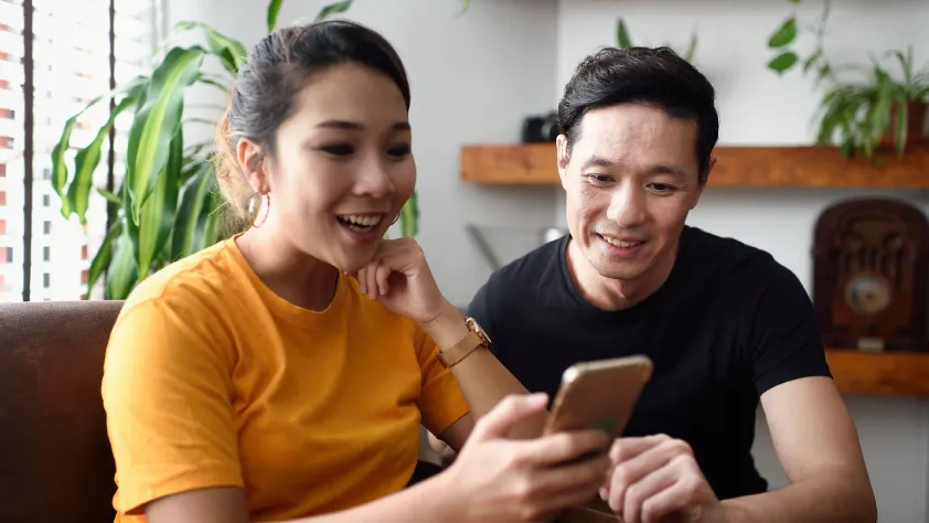 Two people sitting in living room while interacting with a click-to-message ad