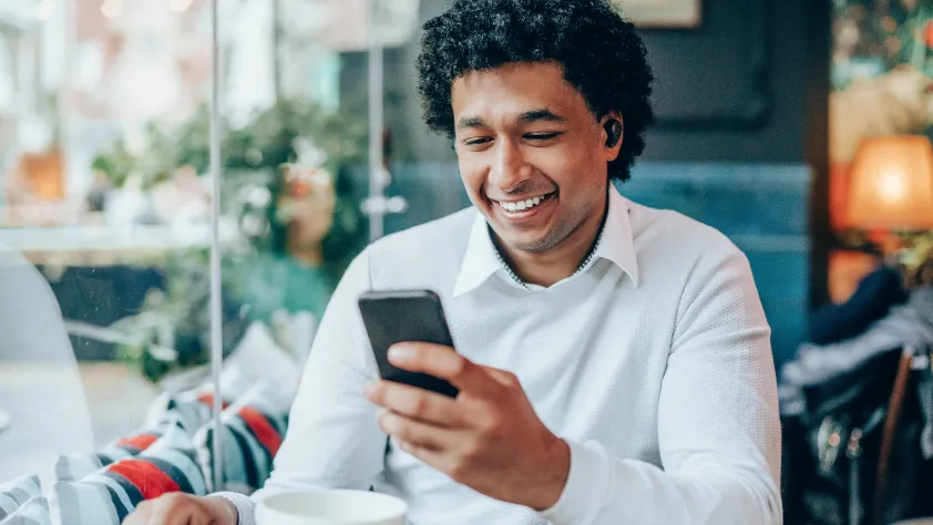 Person sitting in cafe with coffee, smiling, while engaging with a click-to-message ad