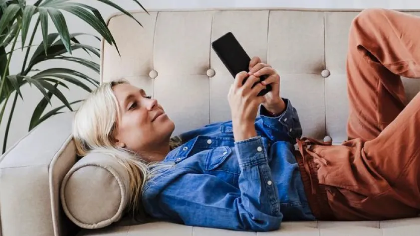 Person laying on couch while looking at a Facebook ad on phone