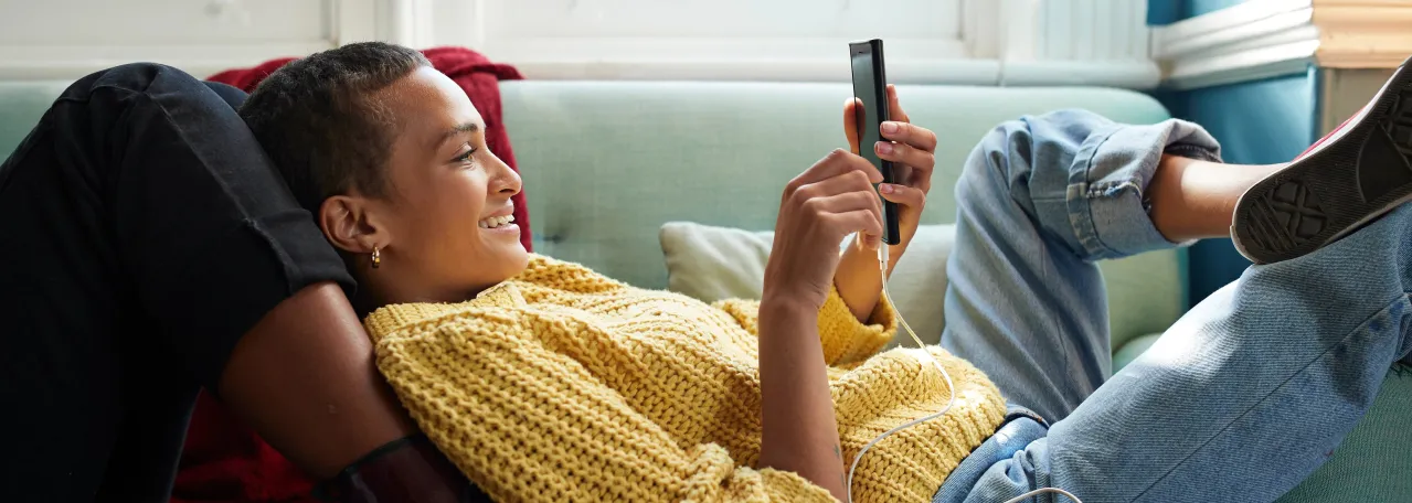 Person laying against someone's legs on couch while reading a WhatsApp business message