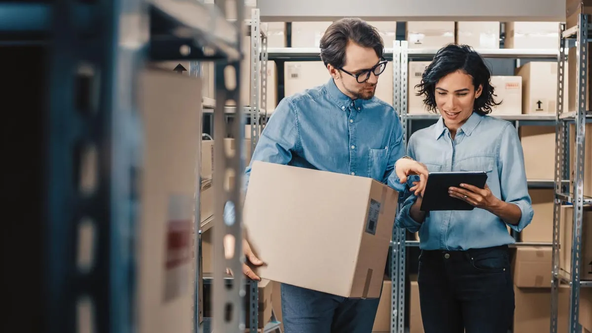 Two workers in a warehouse looking at a tablet