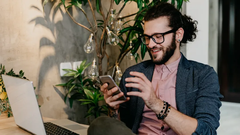 Person sitting at desk and smiling at phone while engaging with a click to message ad