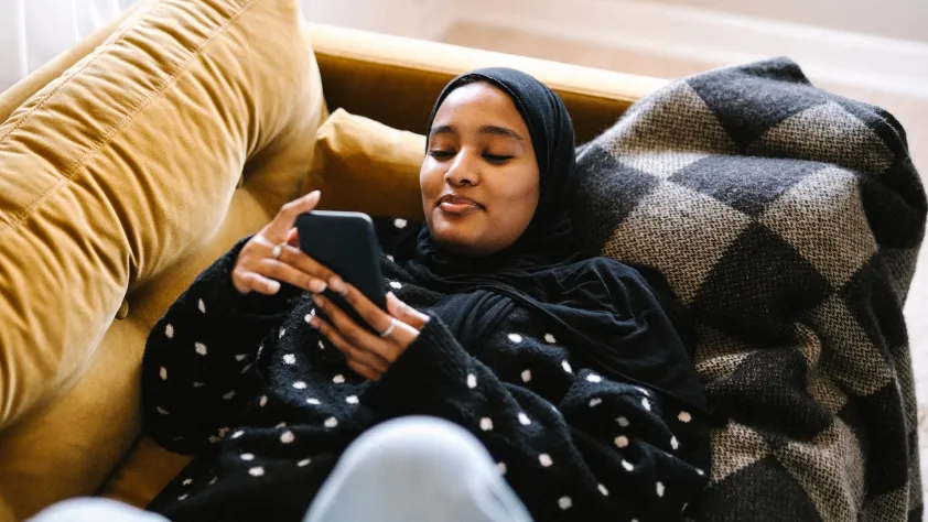 Person laying on yellow couch while reading a personalized message on WhatsApp