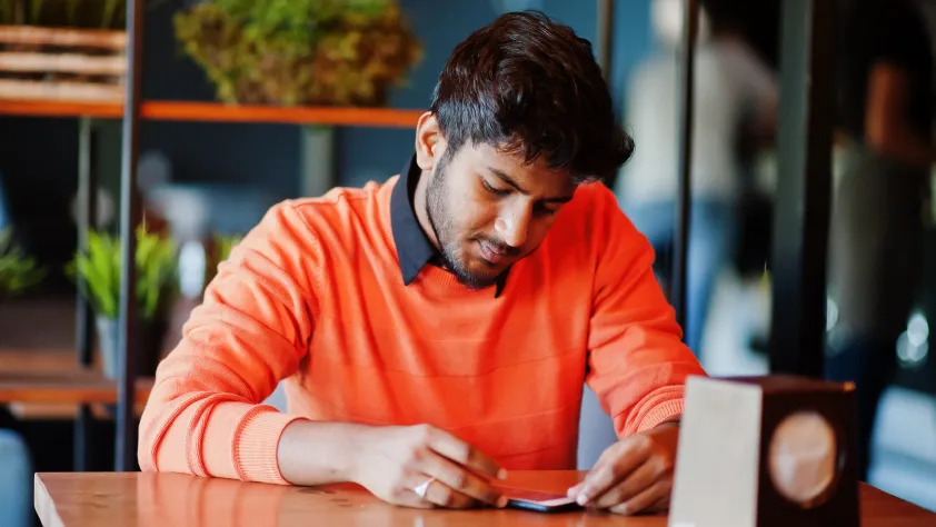 Person sitting in office with plants in the background while making a purchase from a WhatsApp message