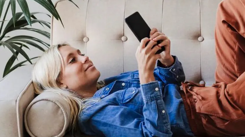 Person laying down on beige couch while reengaging with a business via WhatsApp