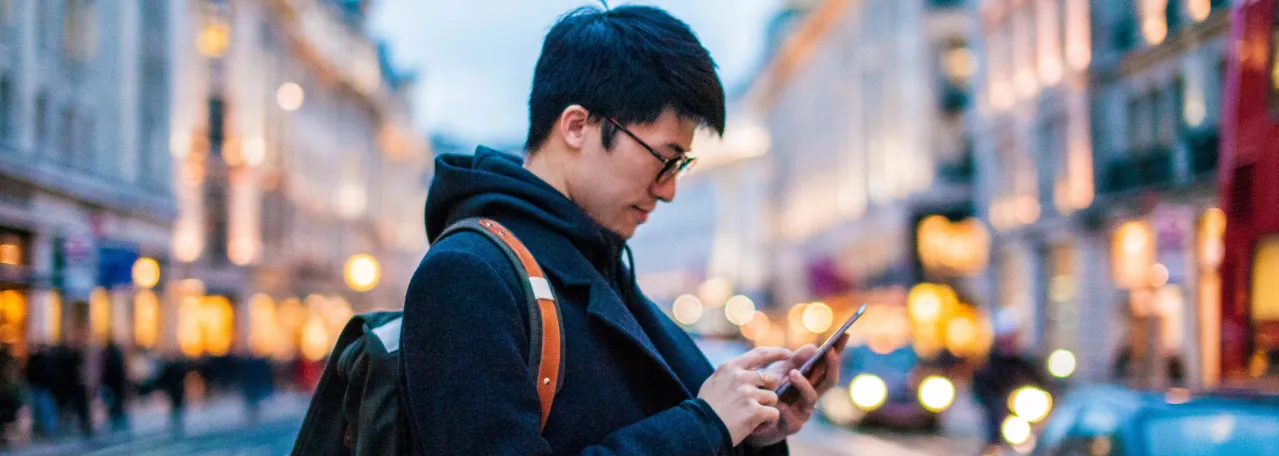Person standing in middle of lit up street while reading a WhatsApp message on phone