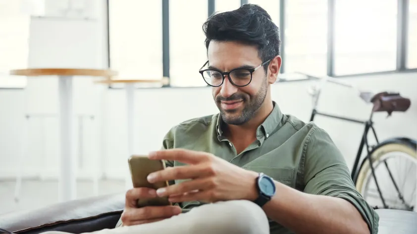 Person sitting in bright office with a bike in the background while reading a business message via WhatsApp on phone