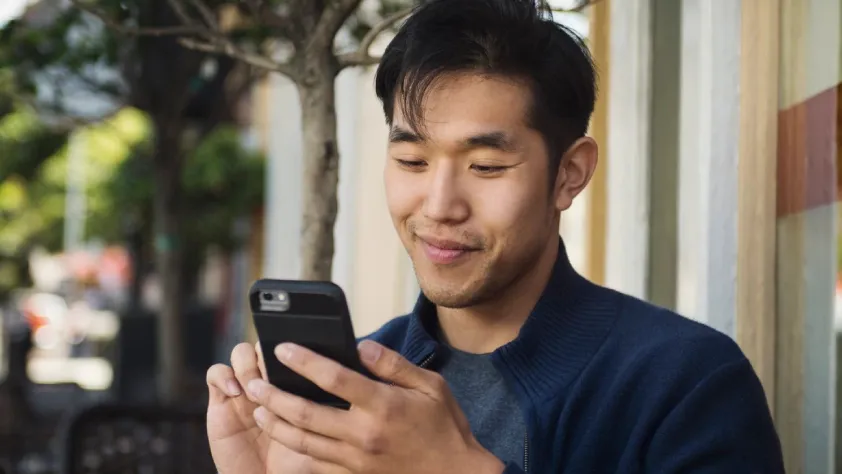 Person sitting outside a storefront while smiling and reengaging with a business through WhatsApp