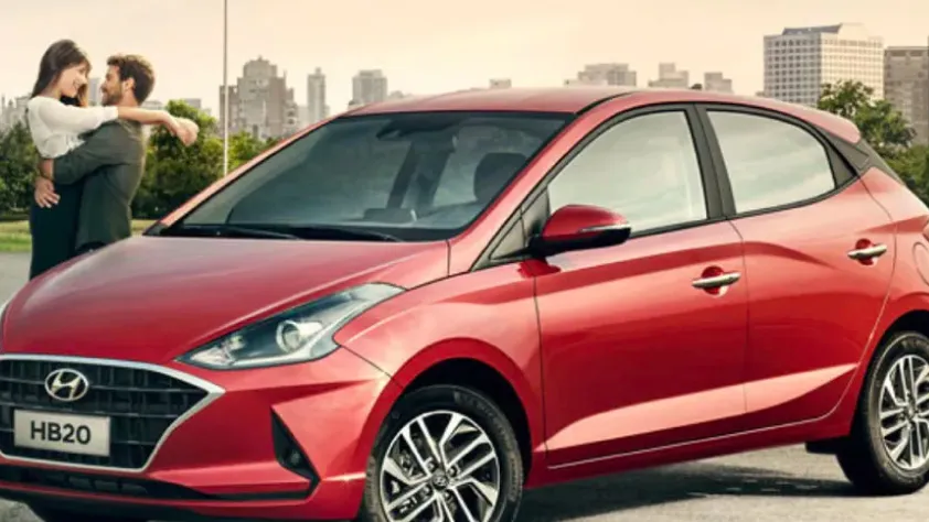 Couple embracing next to a red Hyundai with the city skyline in the background.