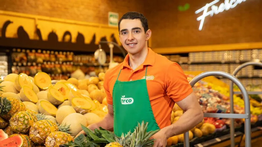 Merco supermarket worker smiling and standing in front of the fruit section