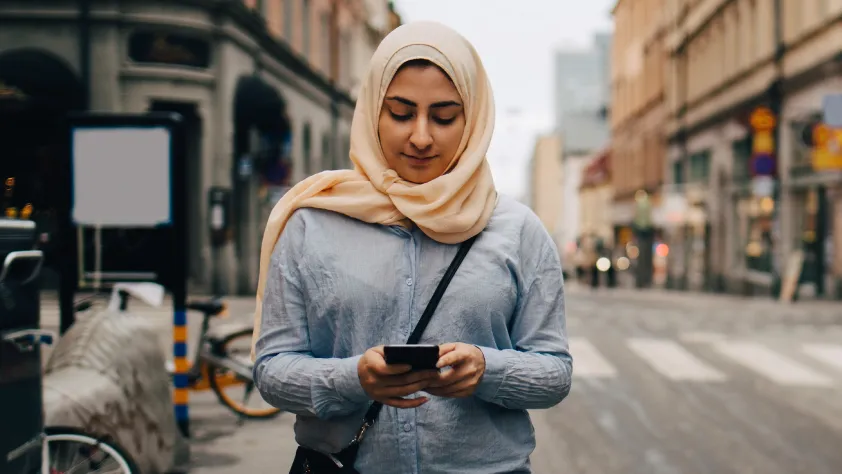 Person walking down the street while reading a WhatsApp message on phone