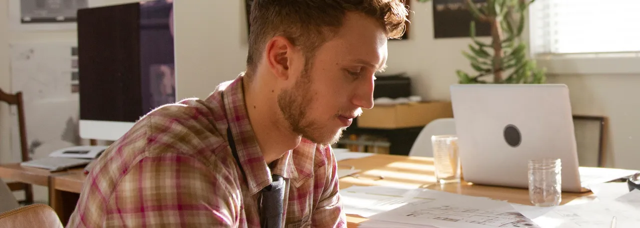 Person sitting at office table and reviewing floor plan designs