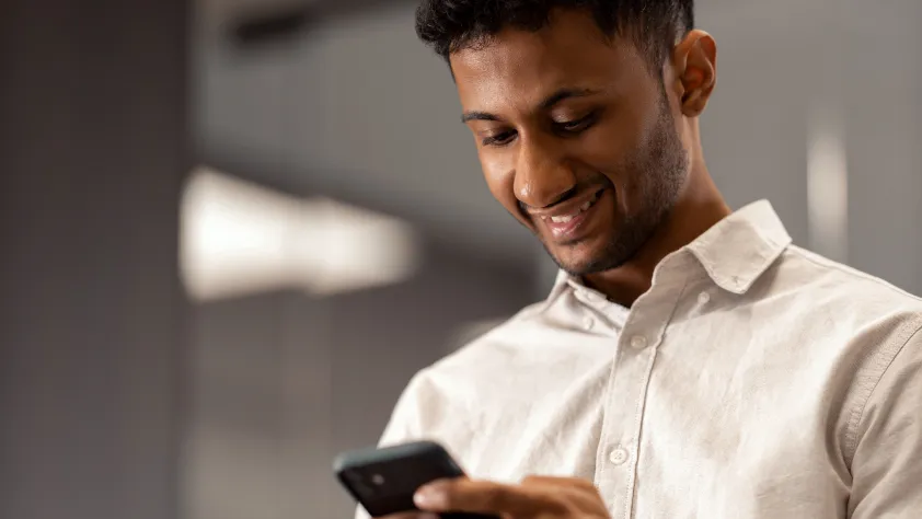 Person wearing a button down shirt while smiling and creating a WhatsApp Business Platform account on their phone.